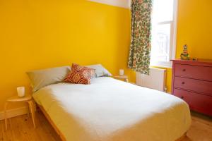 a yellow bedroom with a bed and a window at Stunning 3-bedroom townhouse in superb location in London