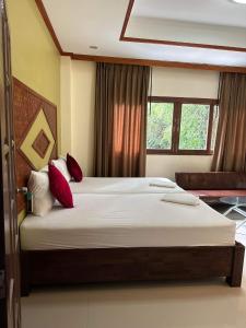 - une chambre avec un grand lit et des oreillers rouges dans l'établissement Buddha Raksa, à Thong Nai Pan Yai