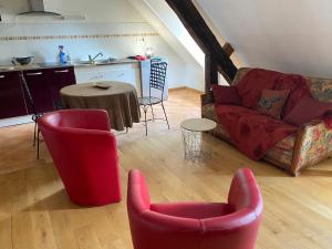een woonkamer met 2 rode stoelen en een tafel bij Loft duplex de charme 8 p plein centre in Lisieux
