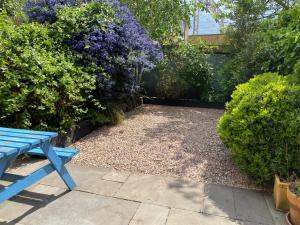 a blue bench sitting in a garden with purple flowers at Stunning 3-bedroom townhouse in superb location in London