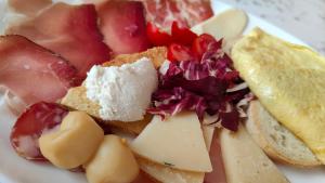 a plate of food with cheese and fruit and bread at Nora Guesthouse Rooms and Villas in Pula