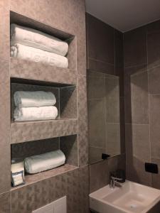 baño con lavabo y toallas en un estante en Qama Hotel, en Pristina