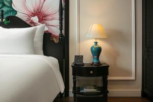 a bedroom with a bed and a lamp on a night stand at Amira Hotel Hanoi in Hanoi