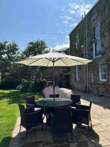 a table and chairs with an umbrella in a yard at Beach lodge with Hot Tub in Ayr
