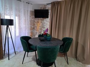 a dining room table with green chairs and a television at jardin kapetanova kuća in Veli Iž +29 photos