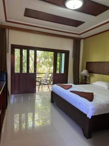 a bedroom with a bed and a balcony with chairs at Buddha Raksa in Thong Nai Pan Yai
