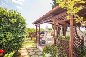 um gazebo de madeira com um banco num jardim em Historic Luxury Villa em Terracina