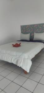 Una cama con sábanas blancas y un objeto rojo. en Hidayah homestay, en Kelimutu