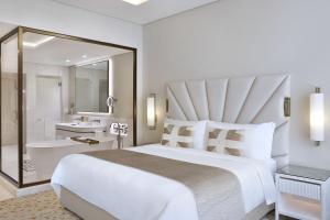 a white bedroom with a large bed and a bathroom at The St. Regis Dubai, The Palm in Dubai