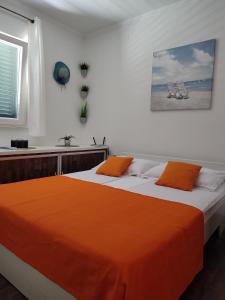 ein Schlafzimmer mit einem Bett mit einer orangefarbenen Decke in der Unterkunft Kuća za odmor TAJANA in Krapanj