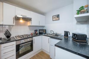 a kitchen with white cabinets and a stove top oven at Train Station Serenity in Staines upon Thames +14 photos