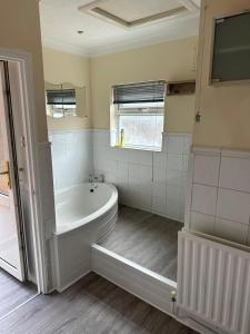 a white bathroom with a tub and a window at Up up and away stays in Norwood