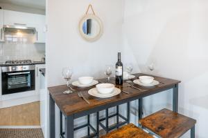 a kitchen with a table with glasses and wine bottles at Train Station Serenity in Staines upon Thames