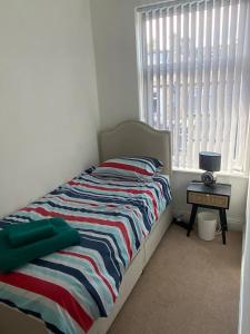 a bedroom with a bed with a striped blanket and a window at Border cottage in Earby