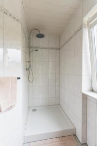 La salle de bains blanche est pourvue d'une douche et d'une baignoire. dans l'établissement Appartment in den Weinbergen bei Mainz - mit 2x Doppelzimmern, 1x großes Wohnzimmer, Bad & Küche, à Stadecken-Elsheim