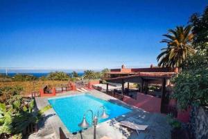 a house with a swimming pool in front of it at The Palm Villa rural beachside in Icod de los Vinos