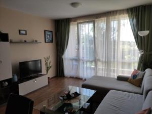 a living room with a couch and a tv at Apartments Atia Resort in Chernomorets