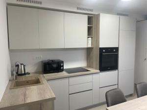 eine Küche mit weißen Schränken, einer Spüle und einer Mikrowelle in der Unterkunft Apartman Martinac in Split