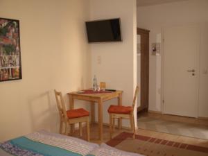 Zimmer mit einem Tisch, 2 Stühlen und einem TV in der Unterkunft Gästehaus in der Gotthardtstraße in Erfurt