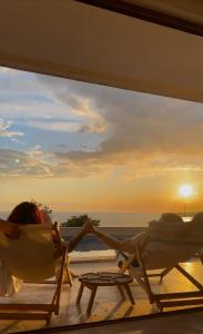 Eine Frau auf einem Stuhl auf einem Balkon mit Sonnenuntergang in der Unterkunft Villa Horus in Sveti Stefan