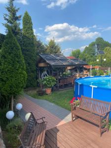 um deque com dois bancos ao lado de uma piscina em Pokoje Gościnne Stawiguda em Stawiguda