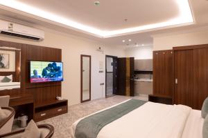 1 dormitorio con 1 cama y TV de pantalla plana en Ramz Al Diyafa 1, en Taif