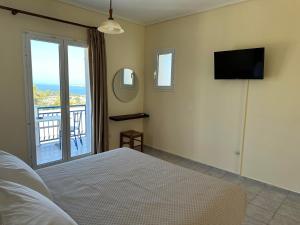 a bedroom with a bed and a television and a balcony at Liberatos Village in Lassi