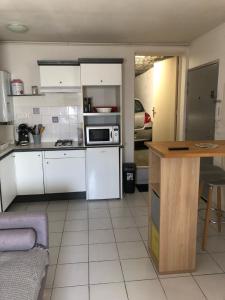 a small kitchen with white cabinets and a table at TheOne Appartement avec garage attenant, entre Montpellier et Sète, près des plages in Villeneuve-lès-Maguelonne