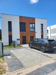 une voiture garée sur un parking devant un immeuble dans l'établissement Bursztynek - Luxoro Park, à Ustka