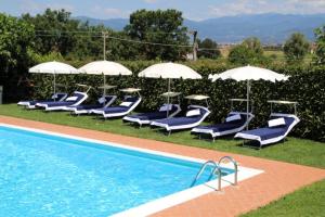 - un groupe de chaises longues et de parasols à côté de la piscine dans l'établissement Corte Vettori, à Quarrata