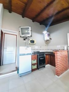 a kitchen with a refrigerator and a tv on the wall at Aromas del Alba in San Clemente del Tuyú