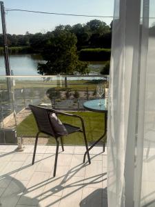 a chair on a balcony with a table and a view of a lake at Lux apartments in Orosháza
