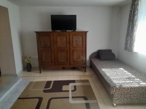 a living room with a tv and a couch and a dresser at Viktória Apartman in Nyíregyháza