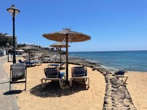 een groep stoelen en een parasol op een strand bij Villa Burgao in Playa Blanca