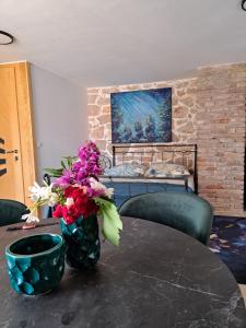 a room with a table with flowers and a painting at jardin kapetanova kuća in Veli Iž