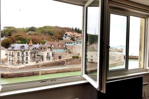 Una ventana abierta con vista a un edificio en Le Duplex, Vue Mer et Port, en Saint-Valéry-en-Caux