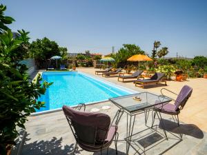 un patio con mesa y sillas junto a una piscina en Fotis Studios Apartments en Gouves