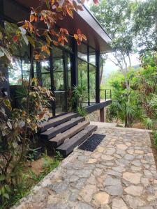 una casa con puertas de cristal y una pasarela de piedra en Wild Cassia, en Haputale