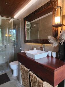 a bathroom with a sink and a toilet and a mirror at Wild Cassia in Haputale