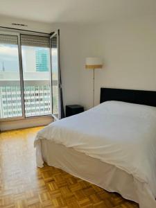 a bedroom with a white bed and a large window at Puteaux, T2 avec Parking près de Paris La Défense by immo kit bnb in Puteaux