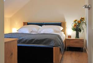 a bed with white pillows and a vase of flowers on a table at Mazury Haus in Ruciane-Nida