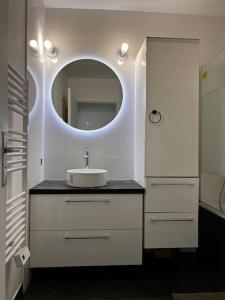 a white bathroom with a sink and a mirror at Puteaux, T2 avec Parking près de Paris La Défense by immo kit bnb in Puteaux