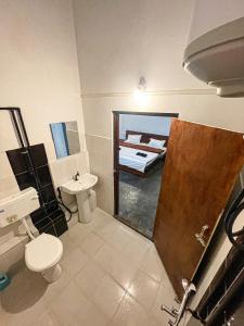 een badkamer met een toilet, een wastafel en een bed bij DA - SAN Stay in Shillong