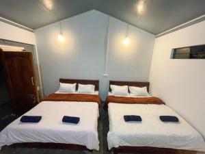 twee bedden in een kleine kamer met witte muren bij DA - SAN Stay in Shillong