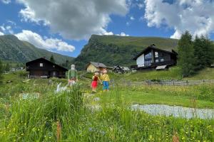 a group of children walking through a field with houses at Heidi-Alm Lodge in Falkertsee