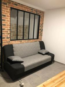 um sofá sentado numa sala com uma parede de tijolos em superbe appartement avec parking à proximité em Sombernon