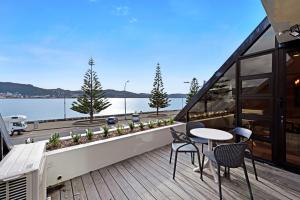 a balcony with tables and chairs and a view of the water at Bay Suites - 328 Oriental Parade Wellington in Wellington