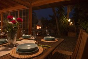 a wooden table with plates and glasses and roses on it at Casa del fuego in Moya