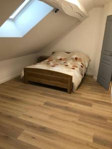 um quarto com uma cama e piso em madeira em superbe appartement avec parking à proximité em Sombernon