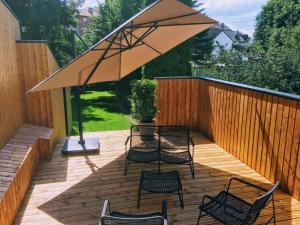 a wooden deck with chairs and an umbrella at Les Ambassadeurs in Spa